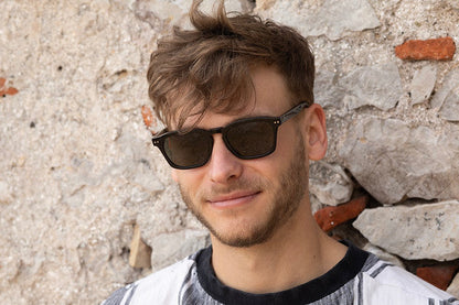 Man wearing Genoa Black sunglasses with green lenses.