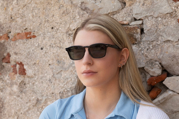 Woman wearing Genoa Black sunglasses with blue lenses.